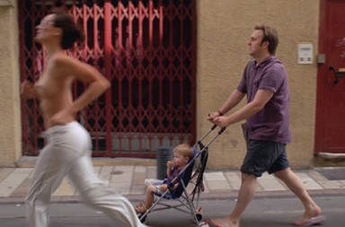 topless woman running man pushing baby